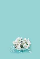 un blanco retro juguete bicicleta entregando blanco manzana flores en un azul antecedentes. San Valentín día tarjeta, cumpleaños regalo, De las mujeres día. entrega de fiesta bienes. primavera concepto con Copiar espacio foto