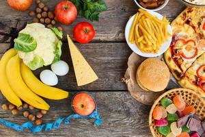 Fastfood and healthy food on old wooden background. Concept choosing correct nutrition or of junk eating. Top view. photo