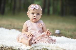 A beautiful little girl on a walk in a summer park. One year old child. Sweet baby. photo