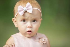 The face of a beautiful little girl on a green background. One year old child. photo