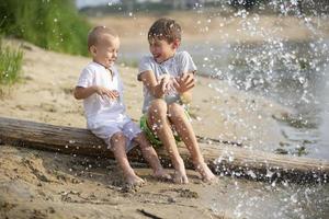 agua salpicaduras son volador a niños jugando en el río banco. foto