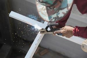 construction man is welding steel roof structure, people working in construction site concept photo