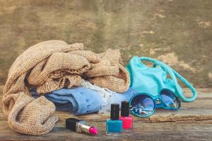 Clothing, women's accessories and cosmetics on old wooden background. Top view. Toned image. photo