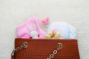 Mother's handbag with items to care for child on white background. Top view. photo