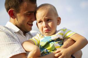 Happy dad comforts his little crying son.Paternity photo