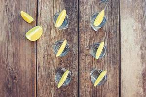 Vodka and lime slices on wooden background. Toned image. Top view. photo