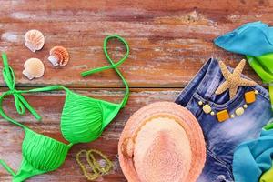 Summer women's clothing and accessories hat, bathing suit, denim shorts, pareo, shells. Top view. photo