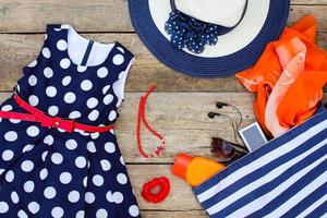 Summer clothing and accessories dress, handbag, headphones, perfume, sunglasses, sunscreen, bonnet and beads. Top view. photo