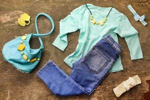 Summer children's clothing t-shirt, jeans, handbag, beads. Top view. photo