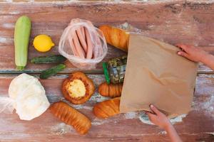 Woman puts purchase of paper bag on table. Top view. photo