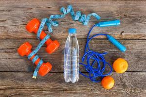 Sports equipment, water and tangerines on old wooden background. Top view. photo