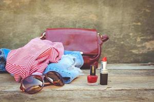 Women's summer clothing and cosmetics on old wooden background. Toned image. photo
