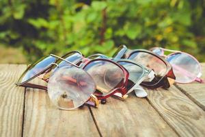 Different sunglasses on wooden background. Toned image. photo