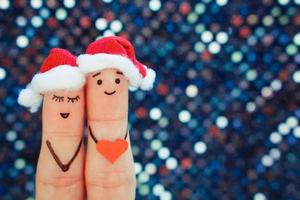 Fingers art of couple celebrates Christmas in new year hats. Toned image. photo