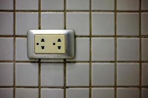 Electrical Outlet with White Ceramic tile Wall. photo