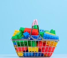Plastic colorful building blocks in a miniature metal shopping cart, educational game for children photo