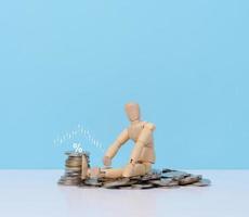 Wooden dummy and a stack of coins, the concept of business collapse, poverty, income decline photo