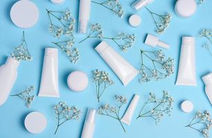 blanco el plastico tubos, frascos, y Gypsophila ramas en un azul fondo, contenedores para cosmético cremas y geles, publicidad y marca promoción foto