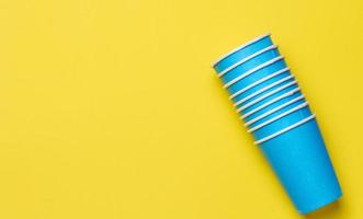 Disposable paper cups on yellow background, top view photo