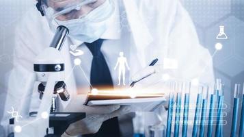 biochemical research scientist working with a microscope for the virus,Doctor man write a history of the experimental results in a , laboratory glassware containing chemical liquid for design. photo