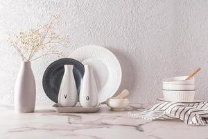 blanco elegante platos en contra el antecedentes de un gris texturizado pared estar en un mármol encimera el concepto de un moderno cocina espacio. foto