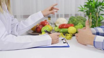 saudável comendo. fêmea nutricionista falando para masculino paciente. a dietista médico conta dela paciente sobre saudável comendo com uma vegetal dieta. video