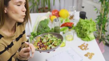 friska äter kvinna gör vegetabiliska diet. äter sallad. kvinna beslutar friska liv äter sallad på tabell full av frukt och grönsaker. video