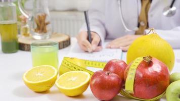 sano comidas y dietético. un dietético trabajando a un lleno de frutas mesa prepara un sano dieta programa. video