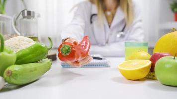 diététicien montrant paprika à caméra dans en bonne santé mode de vie concept. le diététicien femme souligne cette là sont des légumes et des fruits sur le table pour en bonne santé alimentaire. video