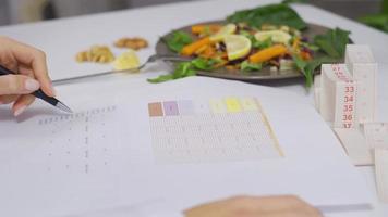 dietético es preparando un vegetal dieta para su pacientes a el mesa. un dietético quien prepara un dieta programa para su pacientes para un sano vida. video