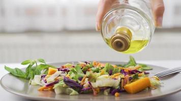 Pouring olive oil on the salad. Eating healthy. Olive oil pouring into vegetable salad. video