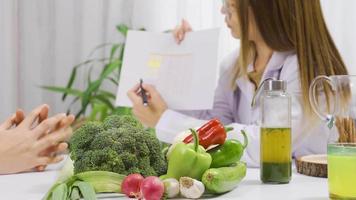 dietologo parla per il suo paziente di un' salutare mangiare dieta. il dietista racconta sua paziente di il dieta programma per un' salutare vita. video