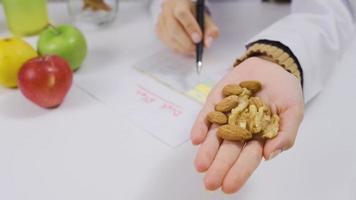 voedingsdeskundige Holding amandelen en walnoten in gezond levensstijl concept. voedingsdeskundige houdt amandelen en walnoten in haar palm. video