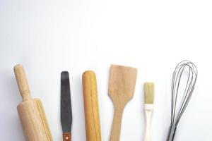 vista superior utensilios de cocina rodillo de madera, espátula de madera y batidor de huevos sobre fondo blanco. materiales o equipos de cocina para panadería. foto