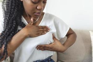 Young African American woman palpating her breast by herself that she concern about breast cancer. Healthcare and breast cancer concept photo