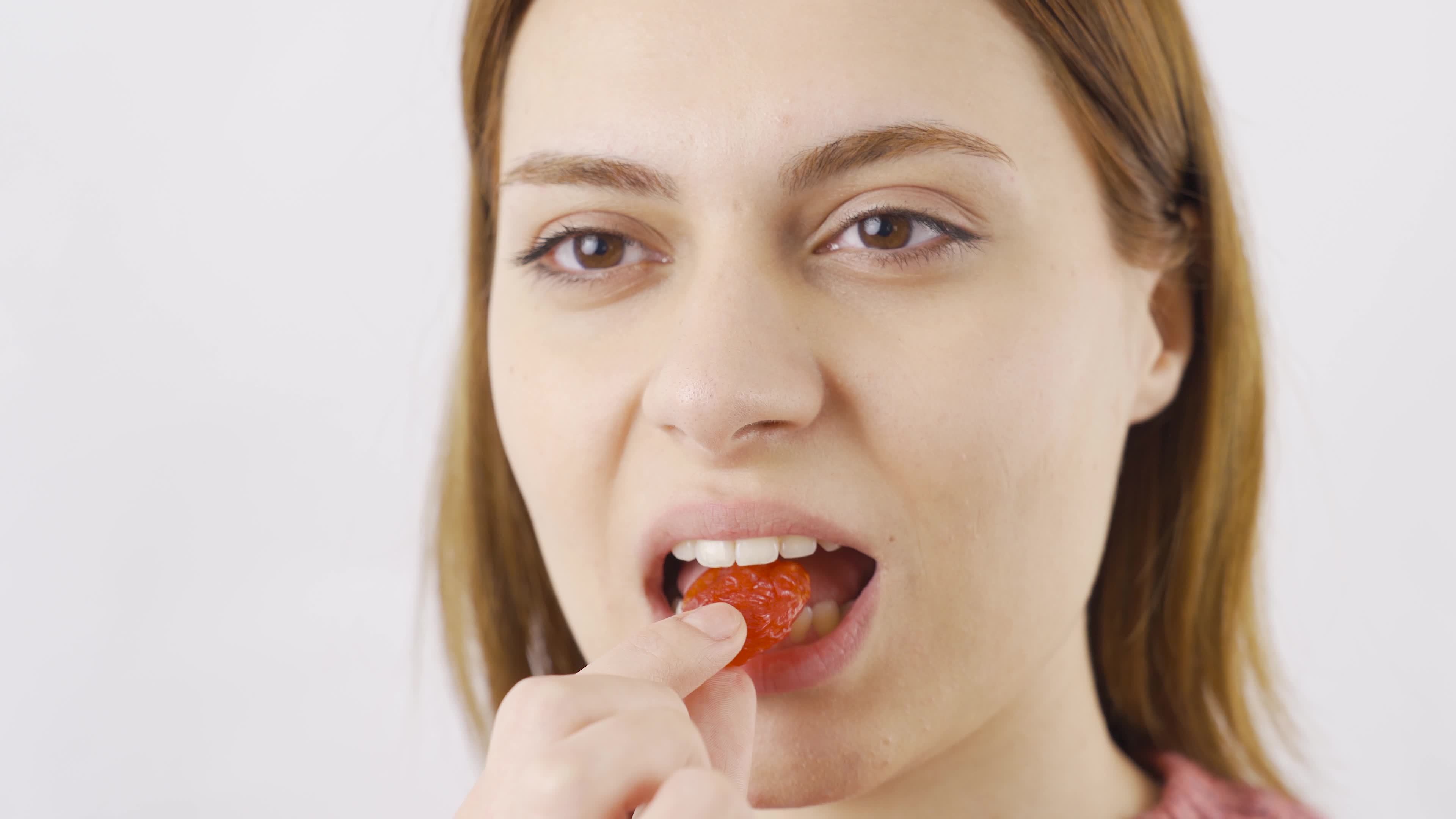 Woman eating dried cherries in closeup. Dry fruits. Closeup woman