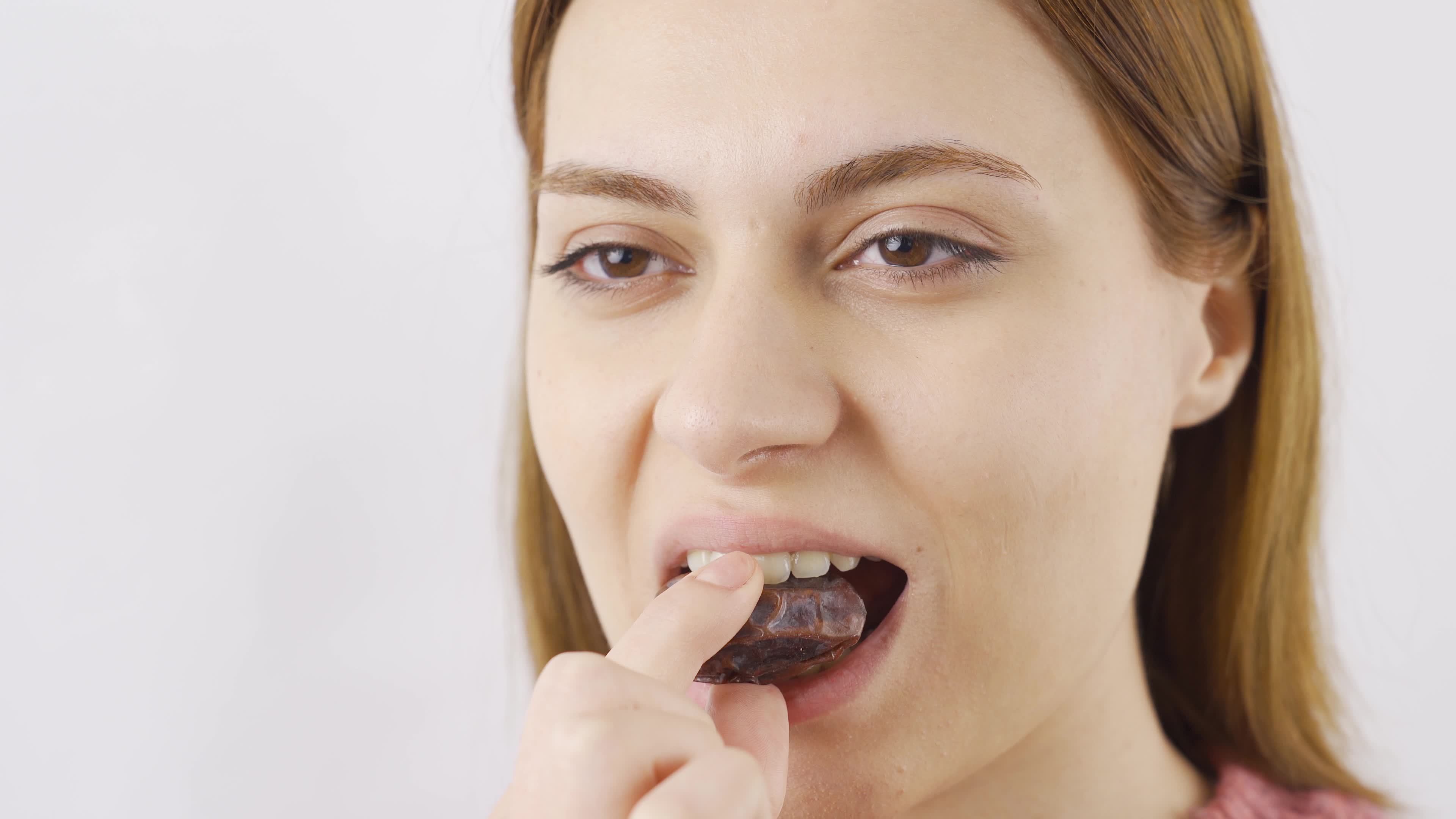 Closeup woman eats fresh dried dates. Woman eating fresh dates in