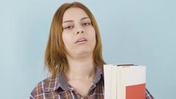 Unhappy schoolgirl is tired of books. The schoolgirl is bored of holding and reading books. video