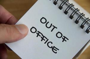 Top view of Out Of Office notification text on white notepad. Business concept photo