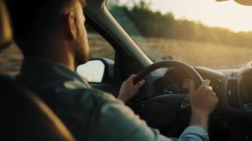 Man drives a car along the road, the setting sun shines in the windshield. video