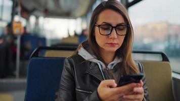Public transport. Woman in glasses in tram using smartphone