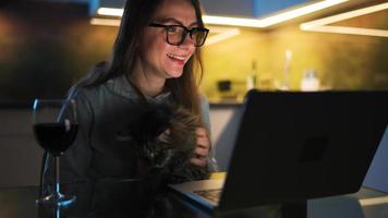 Woman is sitting in the kitchen and working on a laptop at night video