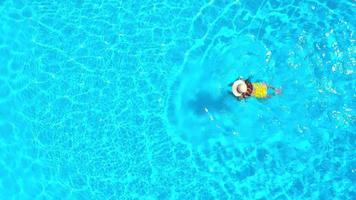aereo Visualizza di un' donna nel giallo costume da bagno nuoto nel il piscina. estate stile di vita video