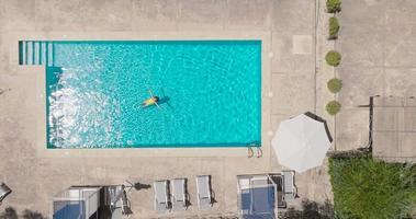 Top down view of a woman in an yellow swimsuit lying on her back in the pool. video