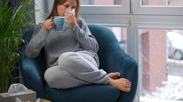 mujer bebidas caliente té y toses dentro un servilleta porque ella tiene un frío, gripe