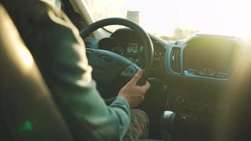 Man drives a car along the road, the setting sun shines in the windshield. video