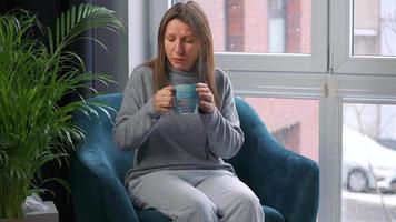 Woman drinks hot tea and coughs into a napkin because she has a cold, flu video