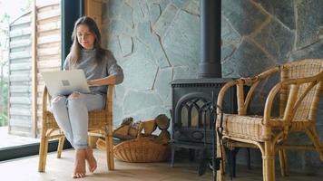 mujer utilizando ordenador portátil mientras sentado cerca el chimenea.