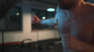 Alone boxer is working out blows on a punching bag in a gym in evening video