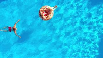 couple ayant amusement dans le piscine, le homme nage et le femme mensonges sur une Donut video